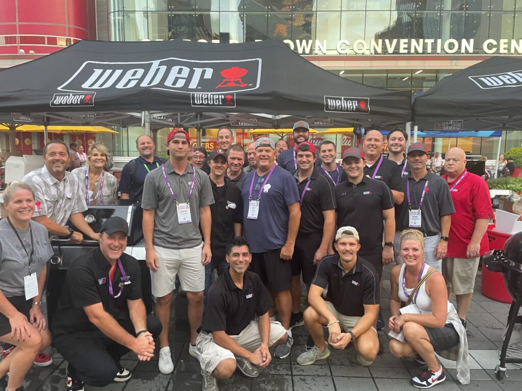 Group photo in front of a Weber grill tent