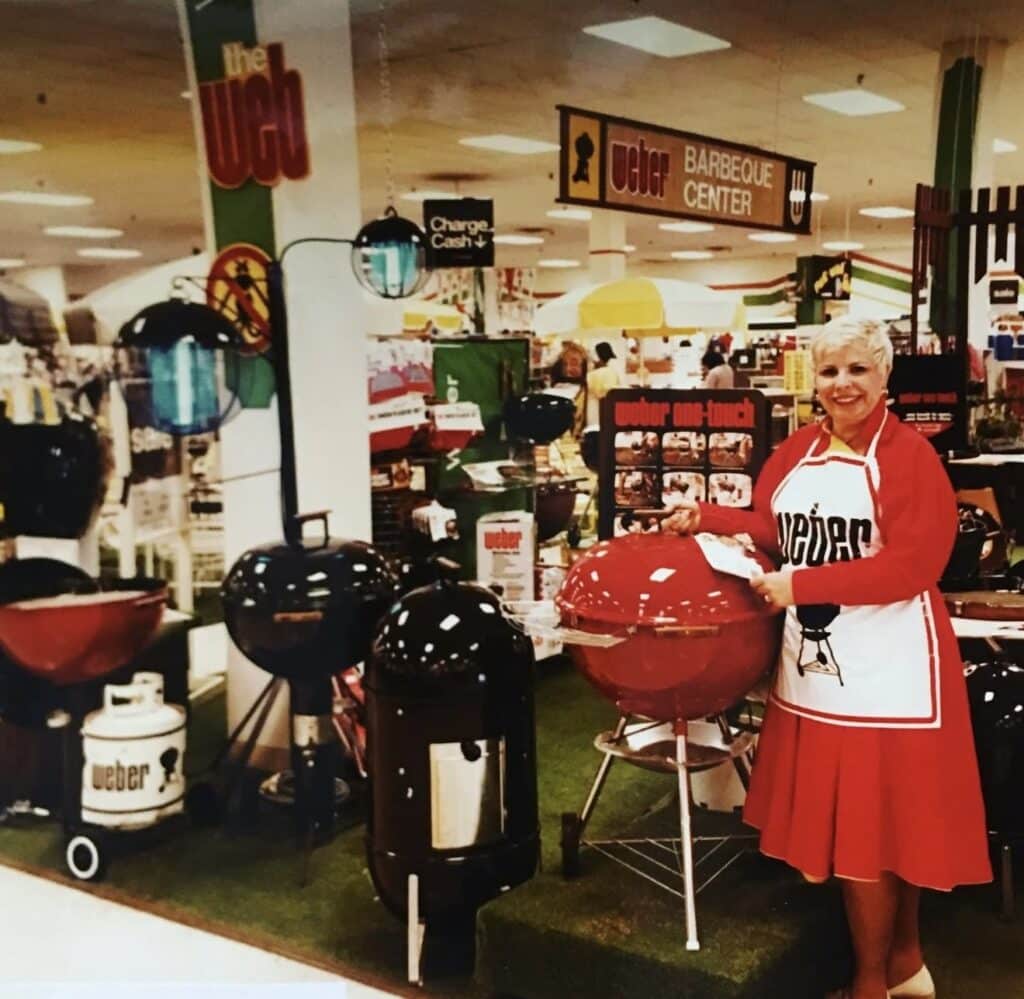 Lady smiling in front of Weber grill products inside of a store