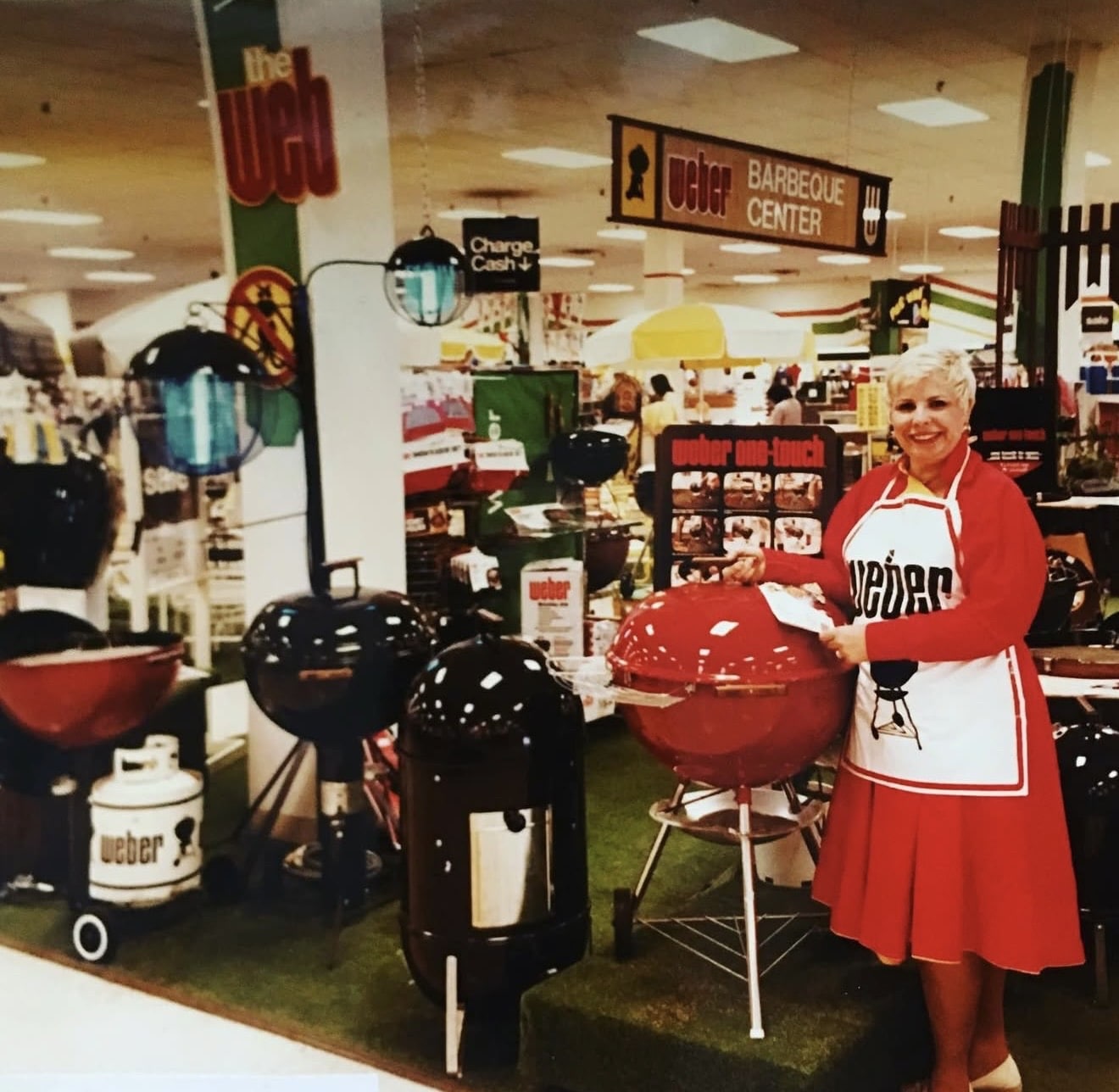 Lady smiling in front of Weber grill products inside of a store