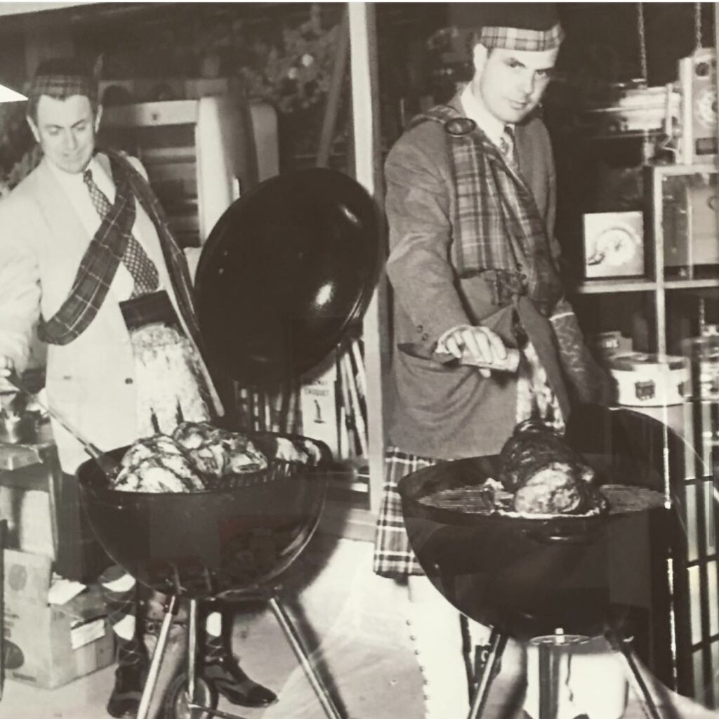 Old black and white photo of two people grilling